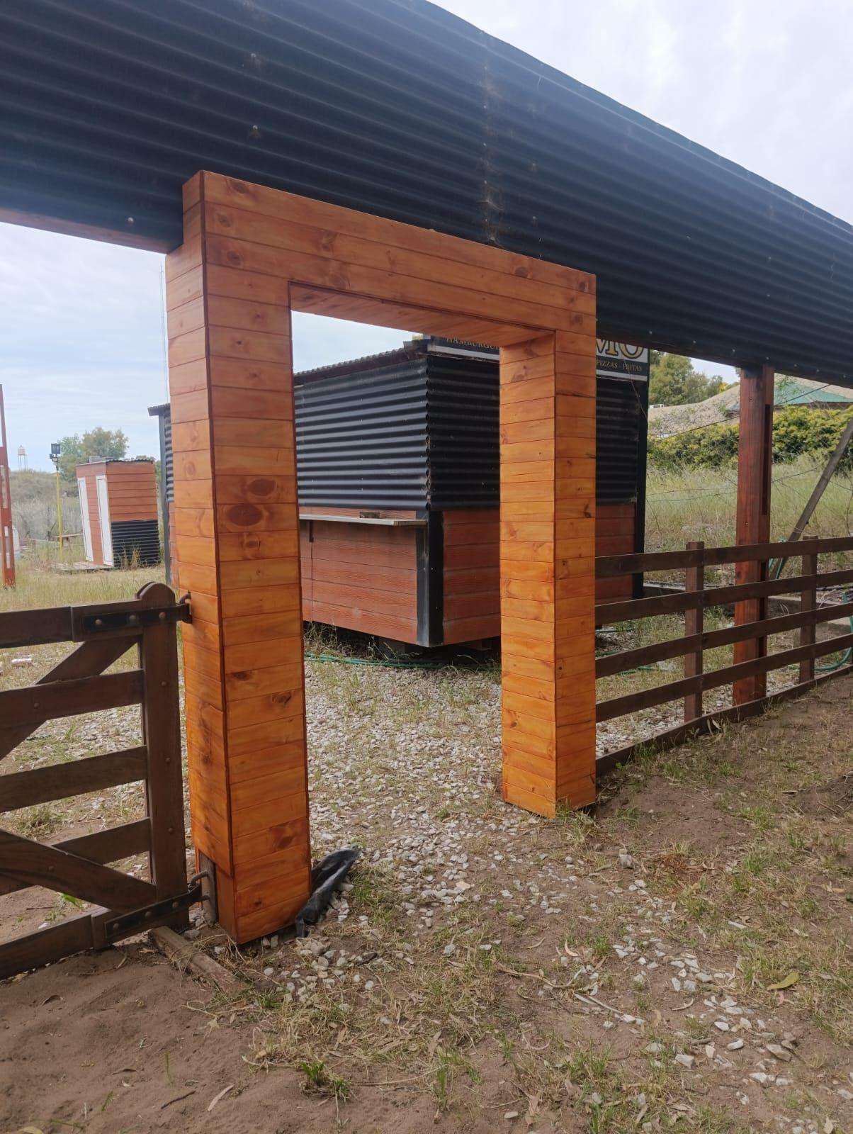 Pórtico de ingreso de madera en un terreno con tranquera