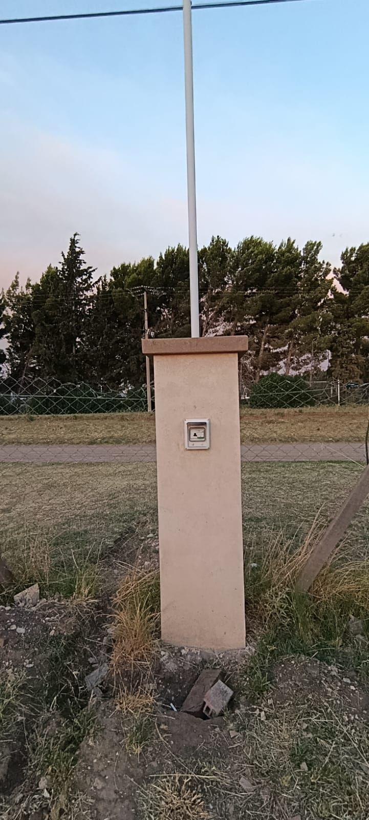 Pilar de luz construido en un terreno, con caño de bajada