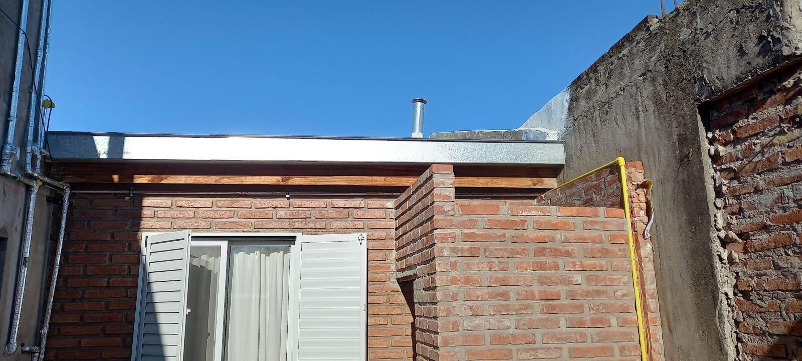 Cañería de gas amarilla instalada sobre la fachada de ladrillo de una vivienda