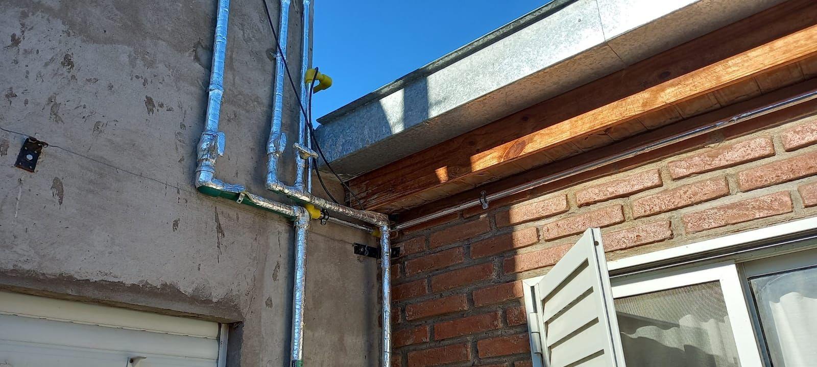 Cañerías instaladas sobre un muro exterior junto a una ventana