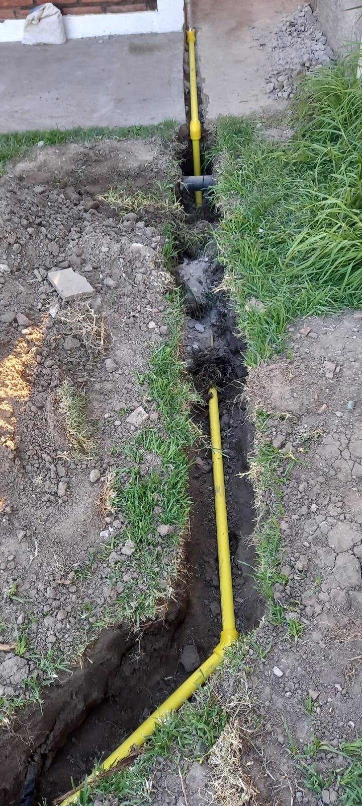 Zanja en un patio con la cañería de gas amarilla colocada
