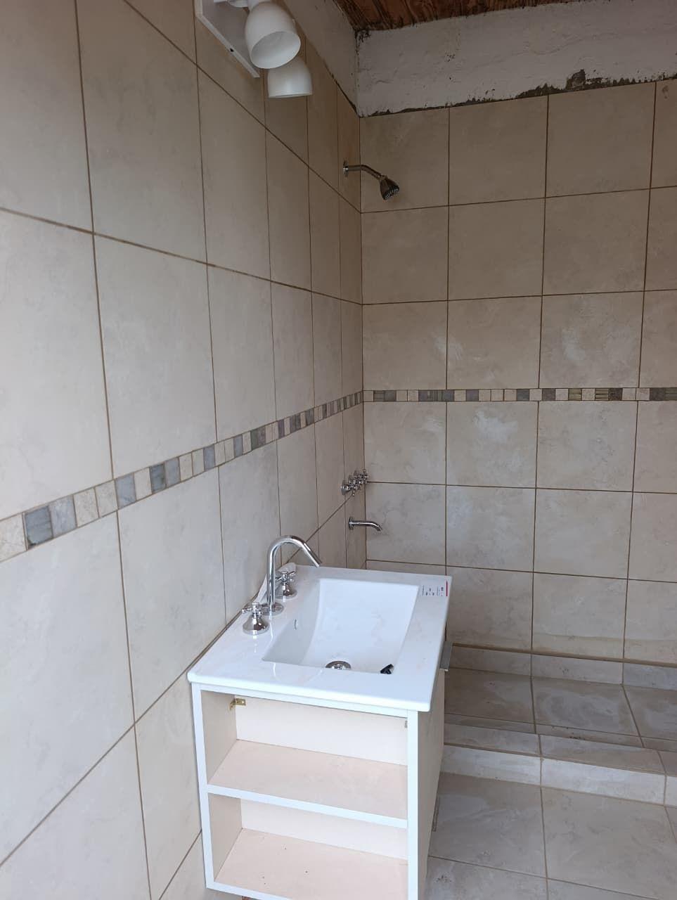 Baño con revestimiento cerámico y bacha sobre mueble blanco